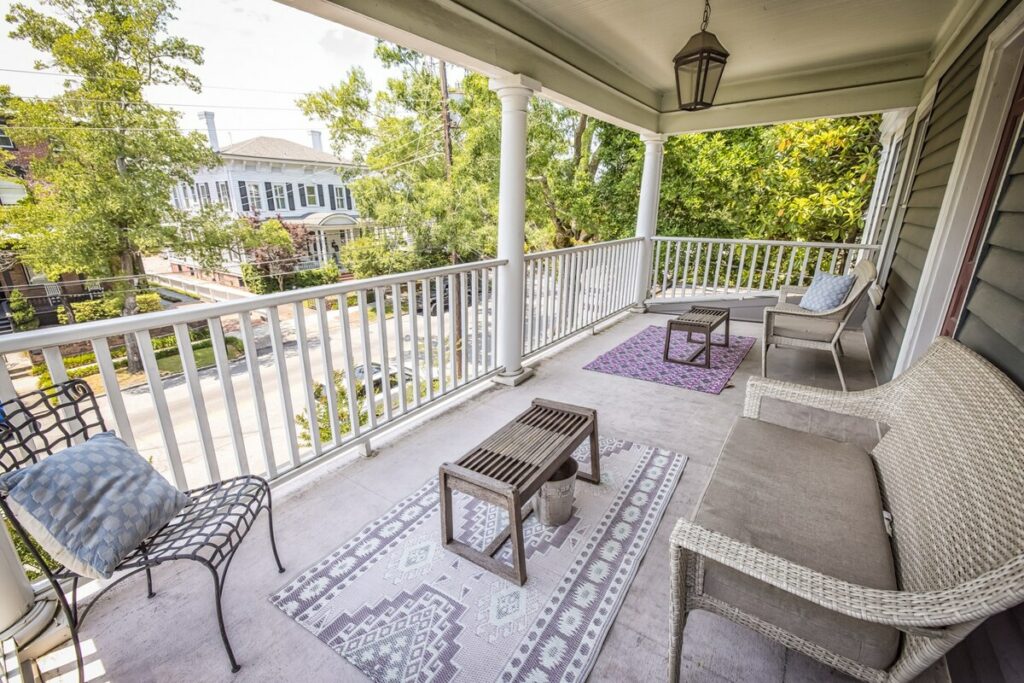 second story balcony porch with chairs, rugs, and coffee table overlooking downtown street Wilmington Vacation Homes