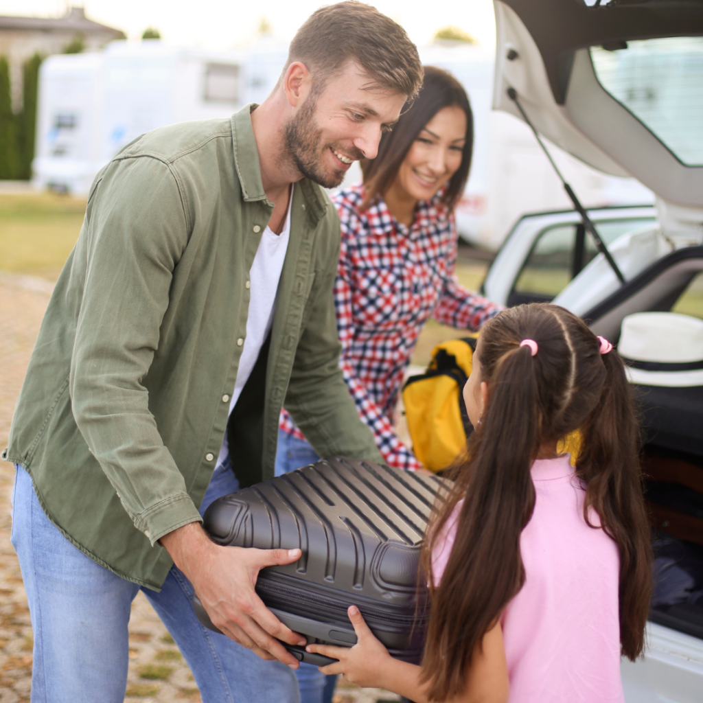 mother and father helping child load luggage into the car for a vacation