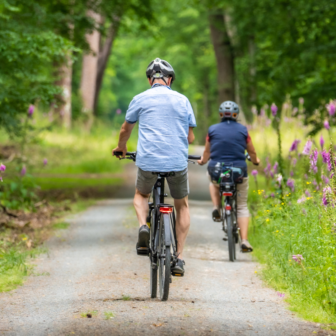 man and woman biking down a path surrounded by flowers and trees Our Favorite Bike paths Wilmington Vacation Homes