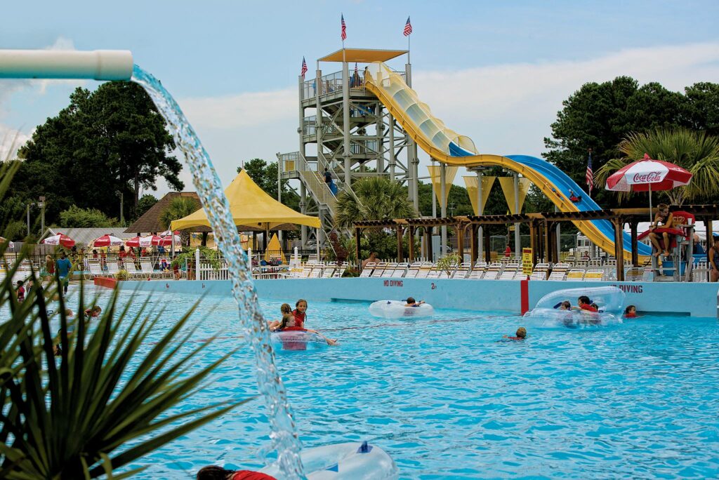 Jungle Rapids water park kids swimming in lazy river with water slide in the background Wilmington Vacation Homes